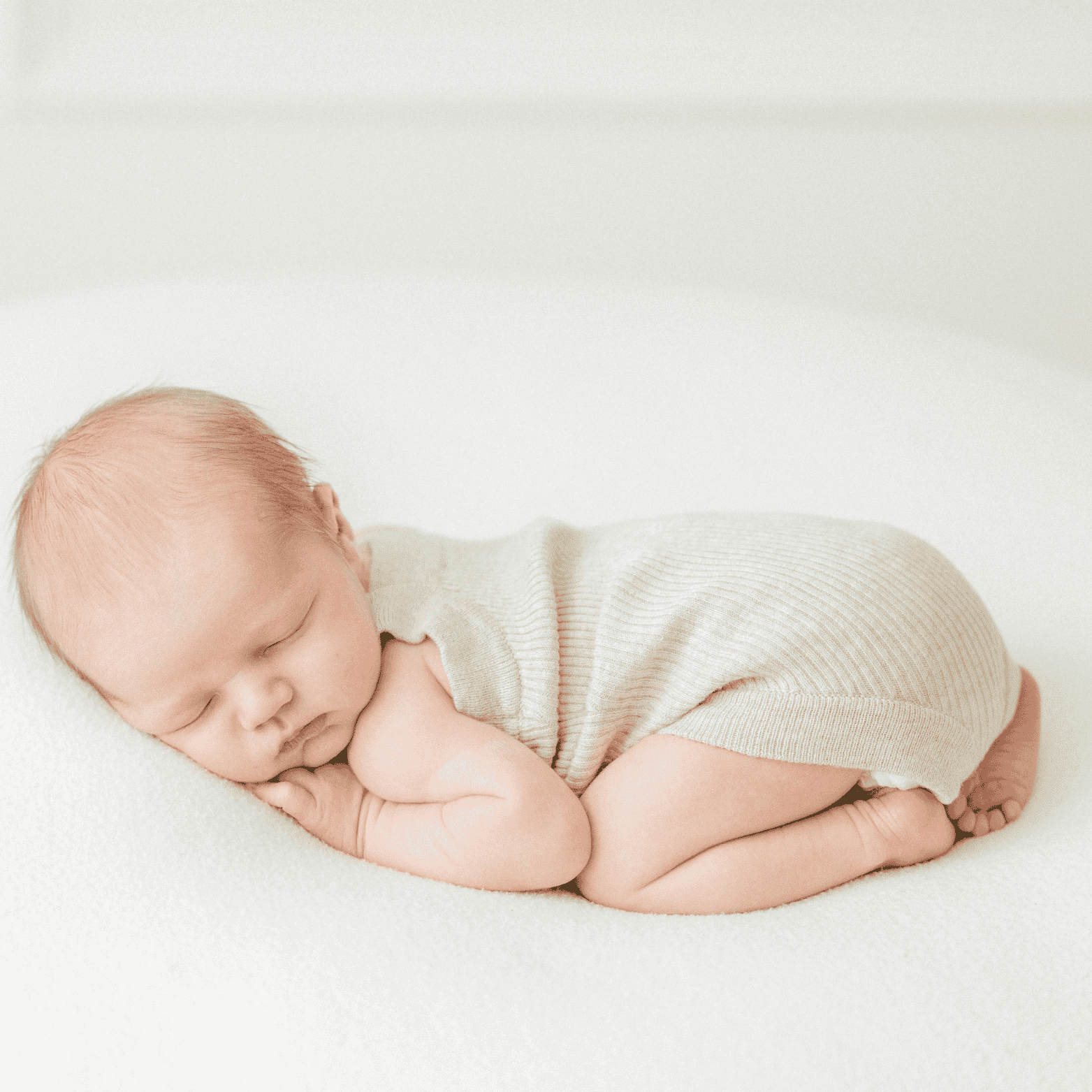 Soft baby sleeping peacefully on a white blanket in neutral clothing, newborn sleep, adorable infant nap, baby crib bedding, peaceful newborn sleep, baby rest, infant comfort, tender baby photograph, serene baby portrait, baby care, BabyDashNow™ essentials delivery service in Stamford, CT.